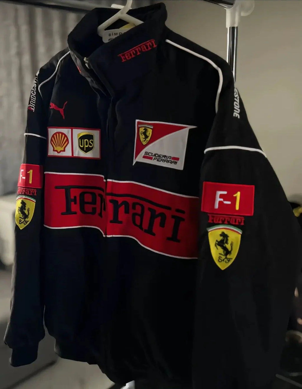 Black jacket with Ferrari and other logos on a hanger
