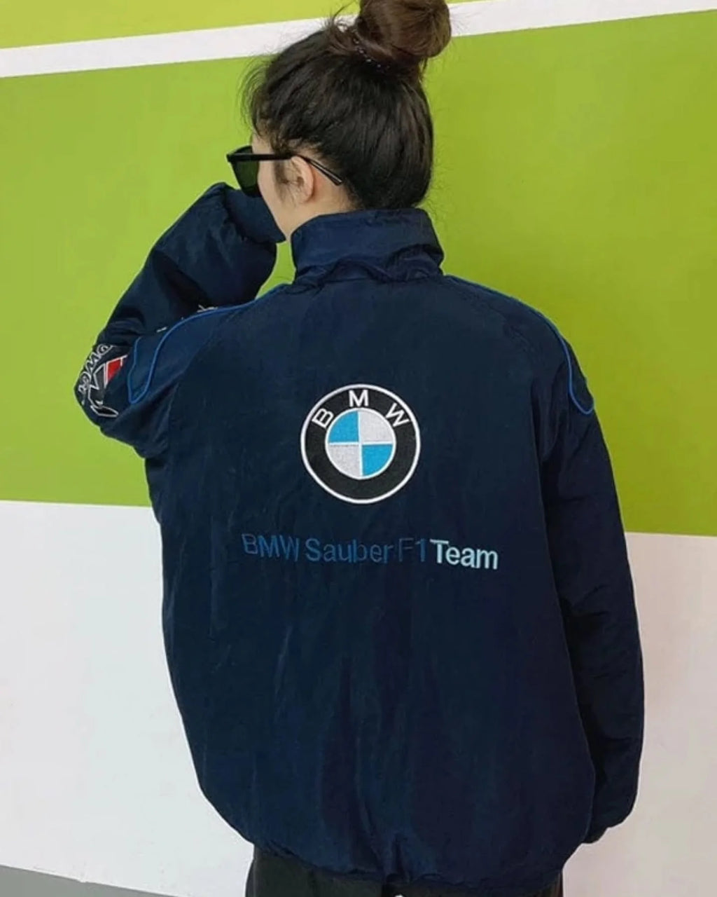 Person wearing a BMW Sauber F1 Team jacket against a green and white background