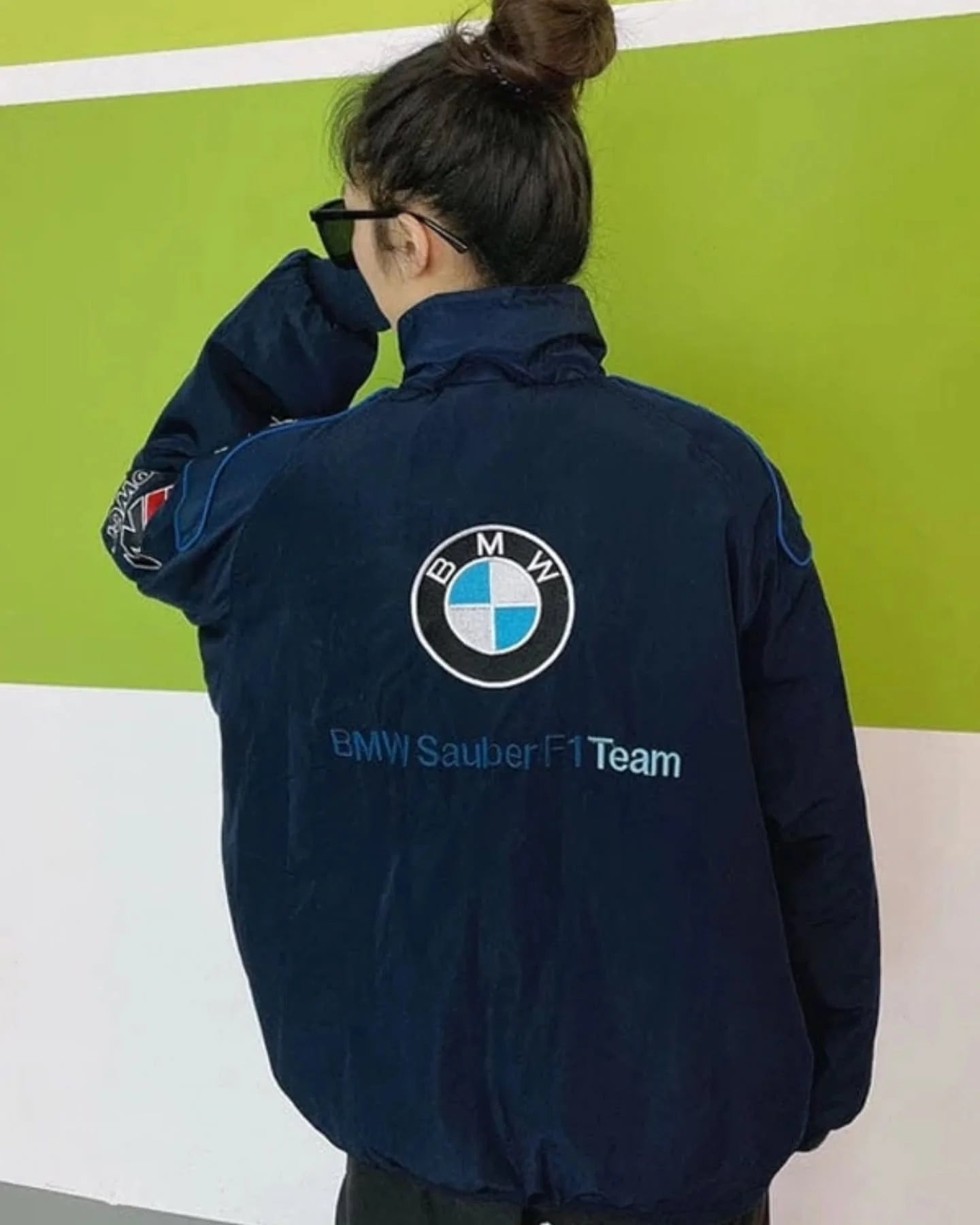 Person wearing a BMW Sauber F1 Team jacket against a green and white background