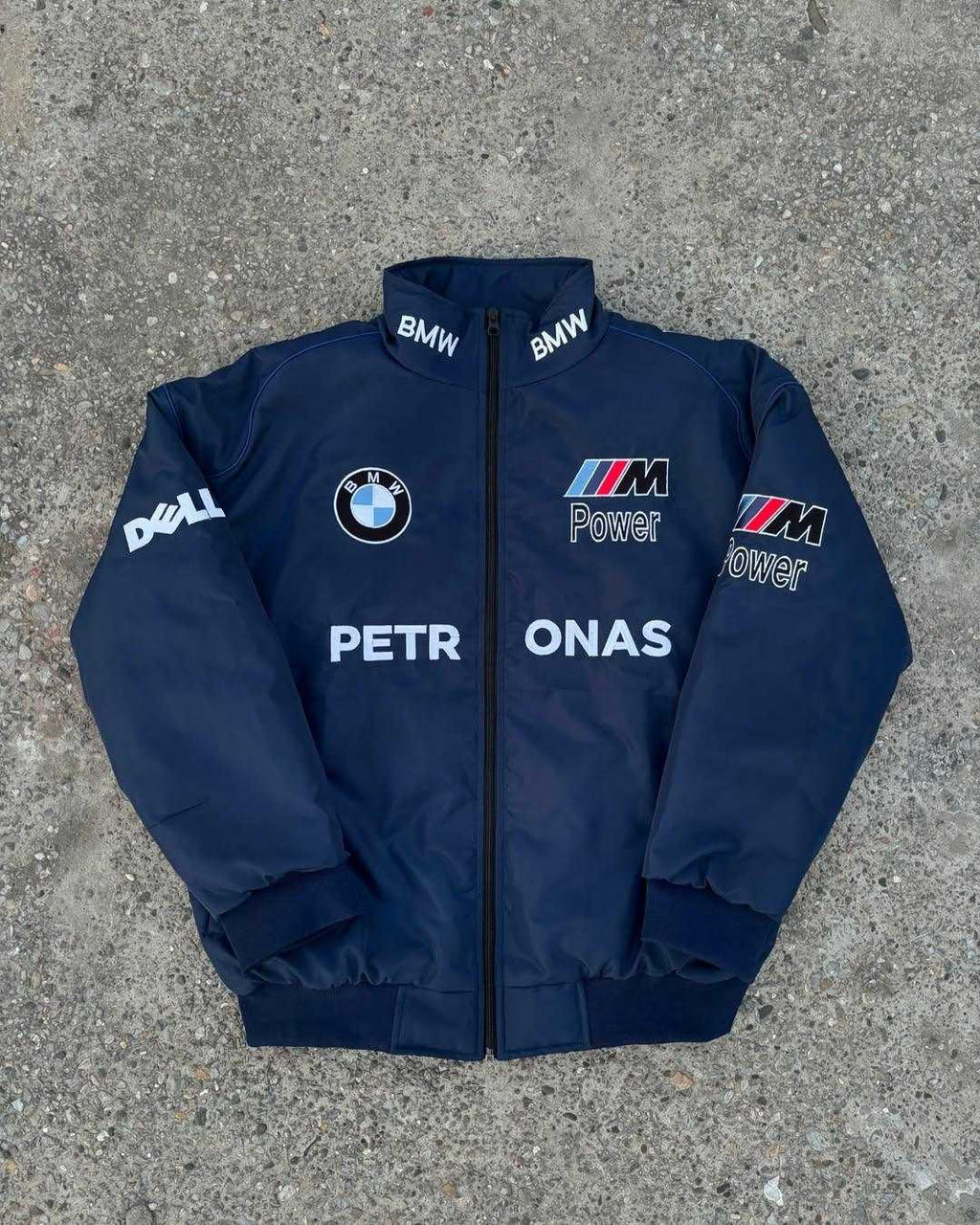Navy blue jacket with BMW and ONAS logos on a concrete surface