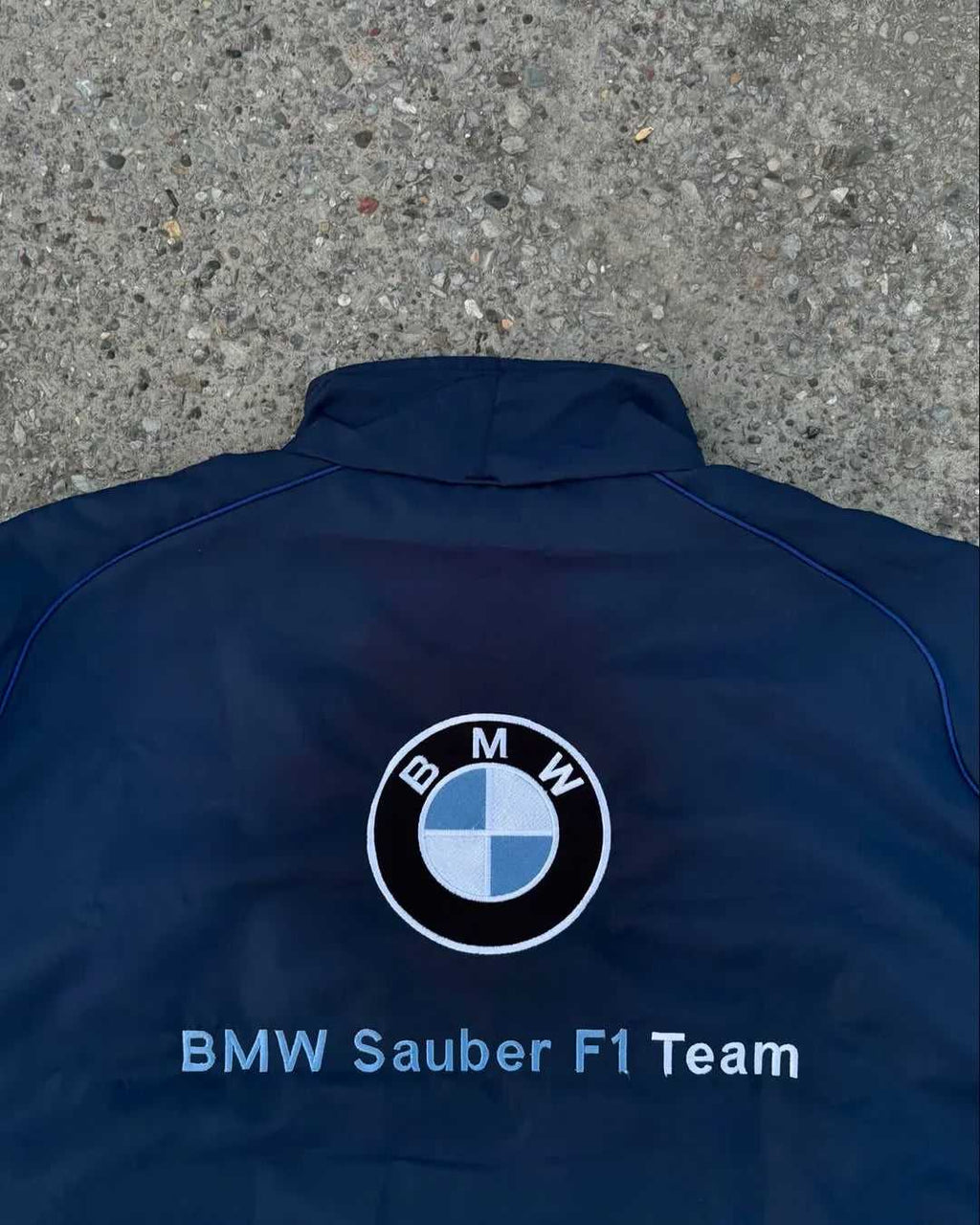 Blue jacket with BMW logo and 'BMW Sauber F1 Team' text on a concrete surface
