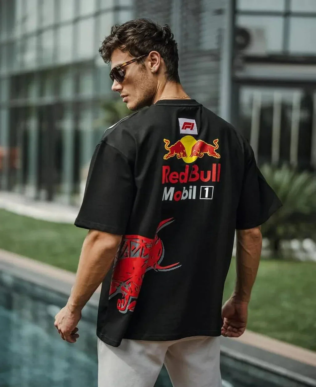 Man wearing a black Red Bull shirt with branding in an outdoor setting