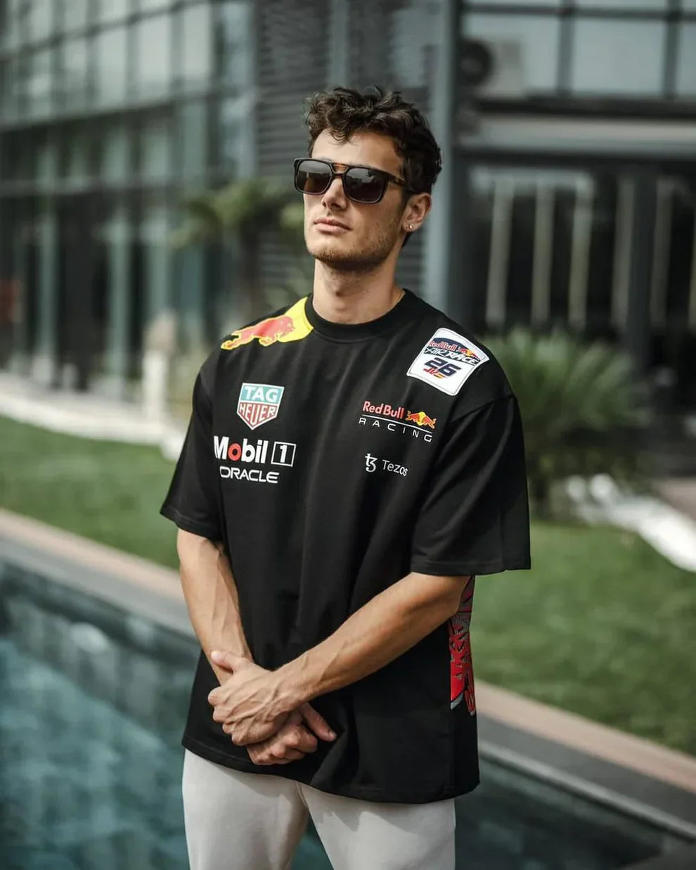 Man wearing a black t-shirt with racing team logos by a pool