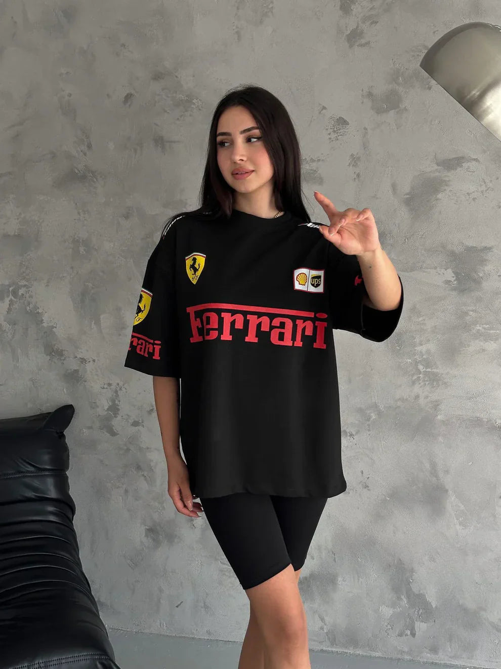 Woman wearing a black Ferrari t-shirt against a gray wall