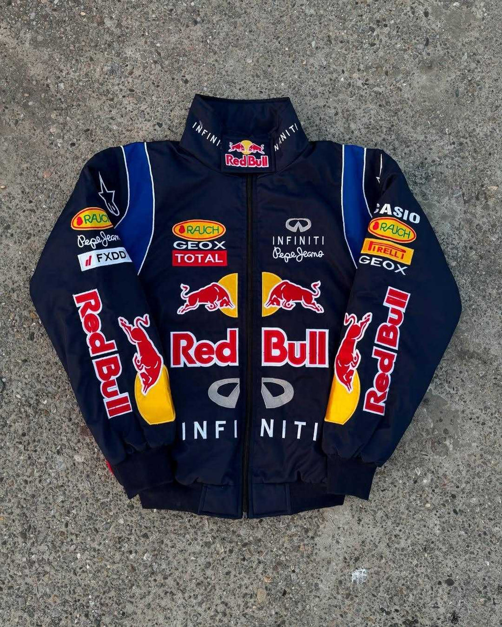 Navy jacket with Red Bull and various sponsor logos on a gray surface