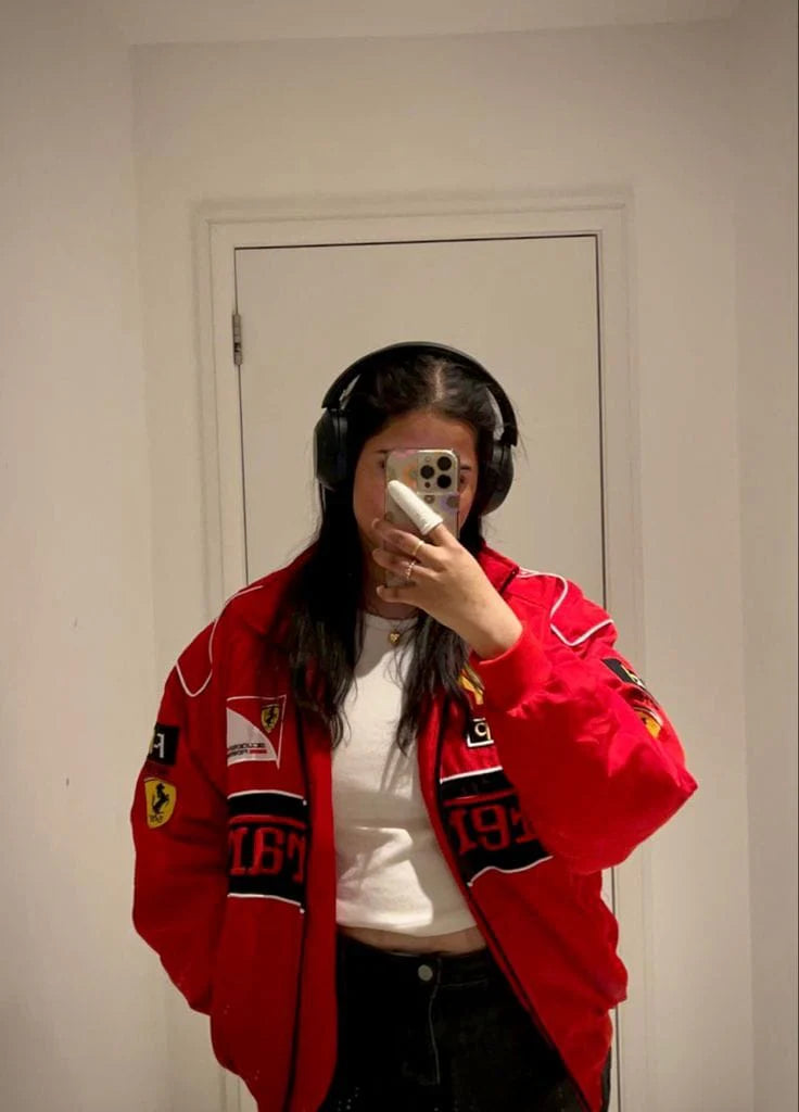 Person wearing a red jacket with patches in front of a white door